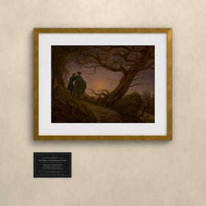 May include: A framed art print of Caspar David Friedrich's Two Men Contemplating the Moon, featuring two figures in dark coats standing on a rocky path beneath a gnarled tree, observing a crescent moon in a twilight sky, with a small plaque below.