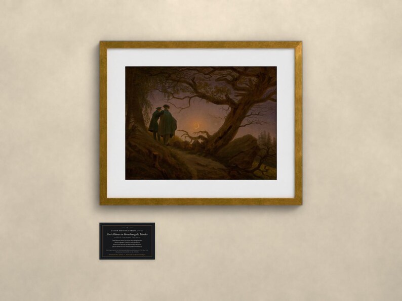 May include: A framed art print of Caspar David Friedrich's Two Men Contemplating the Moon, featuring two figures in dark coats standing on a rocky path beneath a gnarled tree, observing a crescent moon in a twilight sky, with a small plaque below.