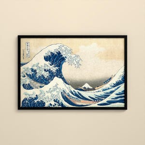 May include: A framed print of The Great Wave off Kanagawa featuring a large, cresting blue wave with white foam, several wooden boats with people, and a distant Mount Fuji, all set against a light beige background with Japanese text.