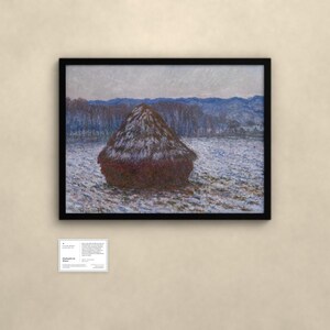 May include: A framed landscape painting featuring a large, dark haystack centered in a snowy field under a pale sky, with blue-toned hills in the distance. Below the artwork, a small white informational placard displays text.