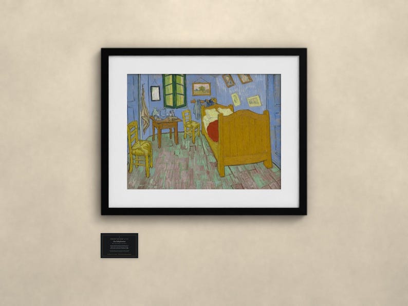 May include: A framed print of Vincent van Gogh's Bedroom in Arles painting, featuring a yellow bed, two yellow chairs, and a wooden table inside a blue-walled room. A small black plaque with white text is mounted below the framed artwork.