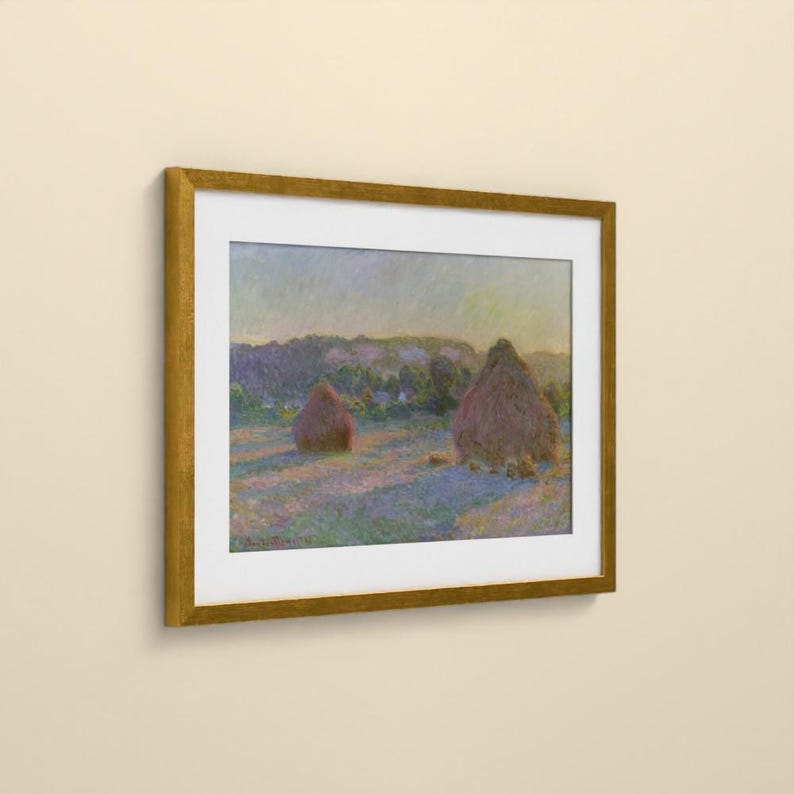 May include: A framed landscape painting featuring two large haystacks in a field during sunset. The artwork displays soft brushstrokes in shades of purple, blue, and gold, enclosed within a simple, metallic gold-colored rectangular frame.