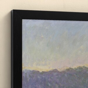 May include: A framed landscape painting featuring a field of purple lavender under a soft, pale blue and yellow sky. The artwork is enclosed in a simple, thin black frame that contrasts with the muted, impressionistic colors of the scene.