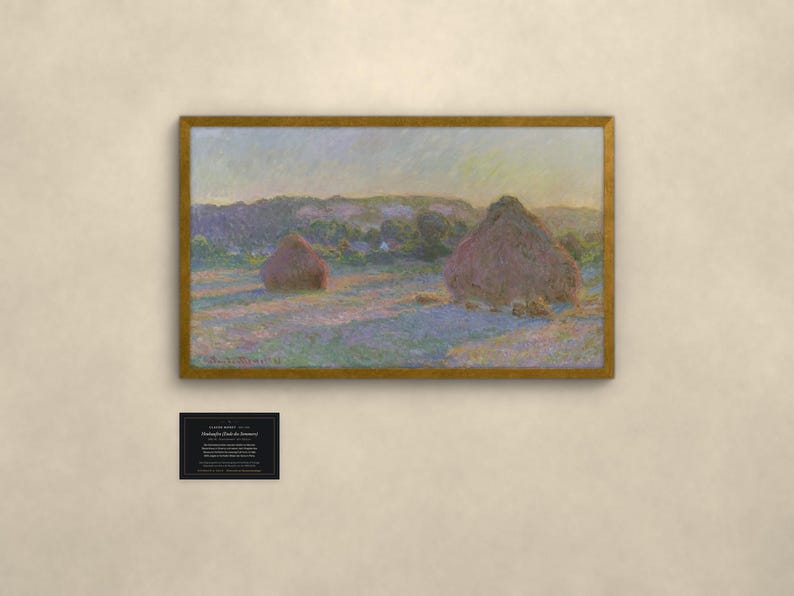 May include: A framed landscape painting featuring two large haystacks in a field under a soft sky, with visible brushstrokes in shades of purple, gold, and green. Below the painting is a small black plaque with white text detailing the artwork.