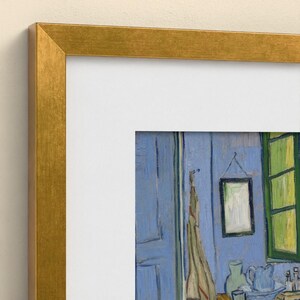 May include: A framed art print featuring a reproduction of a painting with blue walls, a green window frame, a hanging garment, a small framed picture, and a pitcher on a surface, enclosed in a metallic gold-colored frame with a white mat.