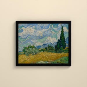 May include: A framed oil painting print featuring a golden wheat field under a swirling blue and white sky. A tall, dark green cypress tree stands on the right side, while a smaller, rounded green bush sits in the center of the field.