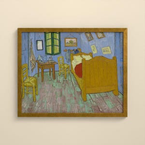 May include: A framed print of a painting depicting a bedroom with a large yellow wooden bed, two yellow chairs, a wooden table, and blue walls. Several small framed pictures hang on the walls, and a cloth hangs near a green window frame.