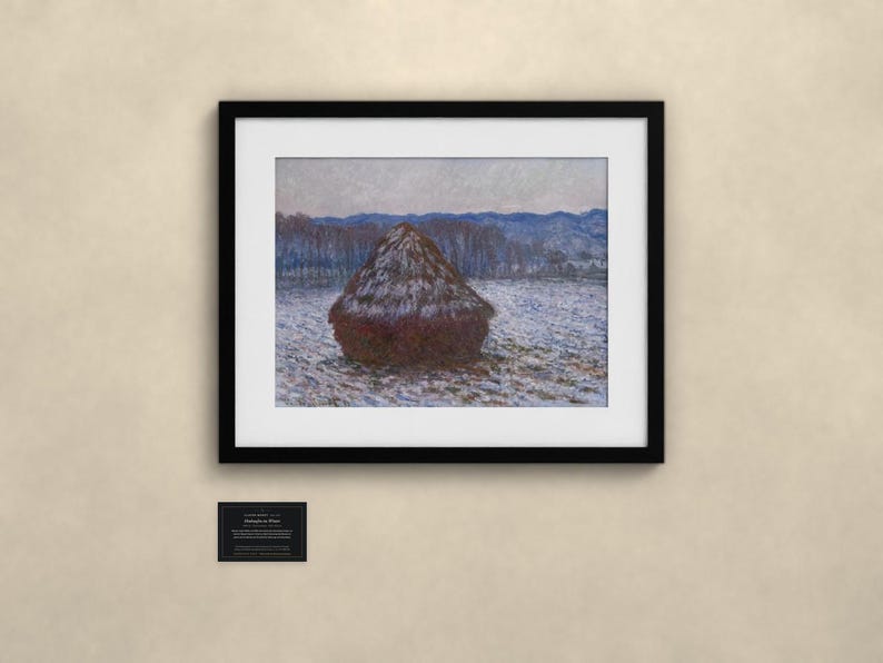 May include: A framed print of a landscape painting featuring a dark, conical haystack centered in a snow-covered field. The background shows blue-toned trees and hills under a pale sky. A small black plaque with white text is mounted below the frame.