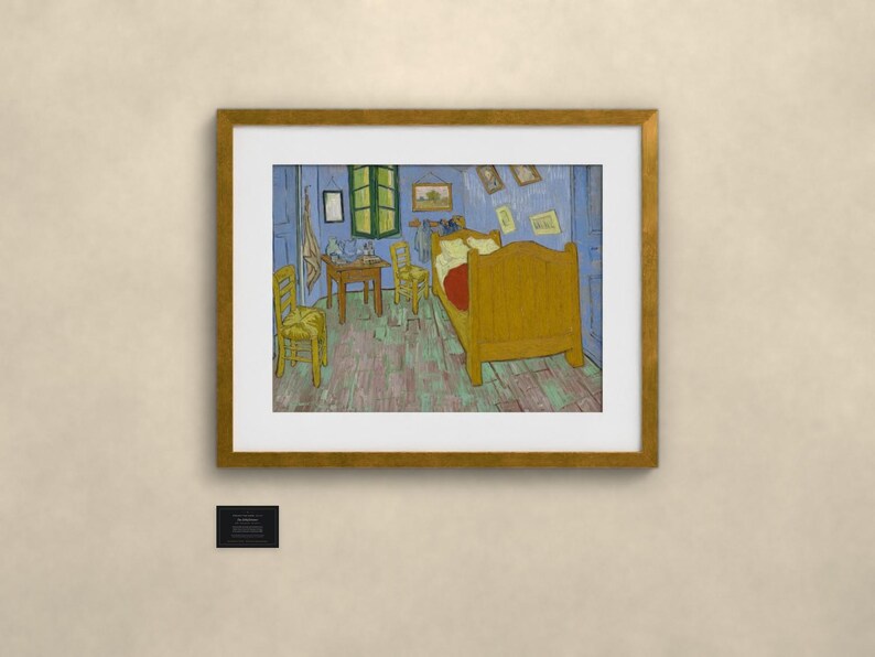 May include: A framed print of Vincent van Gogh's Bedroom in Arles painting, featuring a yellow bed, two yellow chairs, and a small table in a blue room with a green window, enclosed in a gold-colored frame with a white mat and a small black plaque.