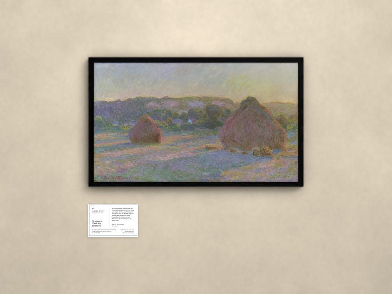 May include: A framed landscape painting depicting two haystacks in a field at sunset, with soft purple and gold light casting long shadows. The artwork is signed Claude Monet 91 in the bottom left corner. A small informational placard is below.
