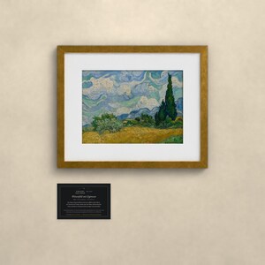 May include: A framed print of Vincent van Gogh's Wheat Field with Cypresses, featuring a golden wheat field, dark green cypress trees, and a swirling blue sky. Below the frame is a small black rectangular plaque with white text.