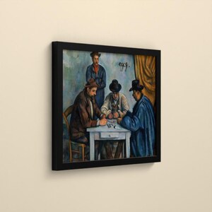 May include: A framed art print depicting a painting of three men sitting at a white table playing cards, with a fourth man standing behind them. The figures wear hats and dark coats in shades of brown, blue, and grey, set against a muted background.