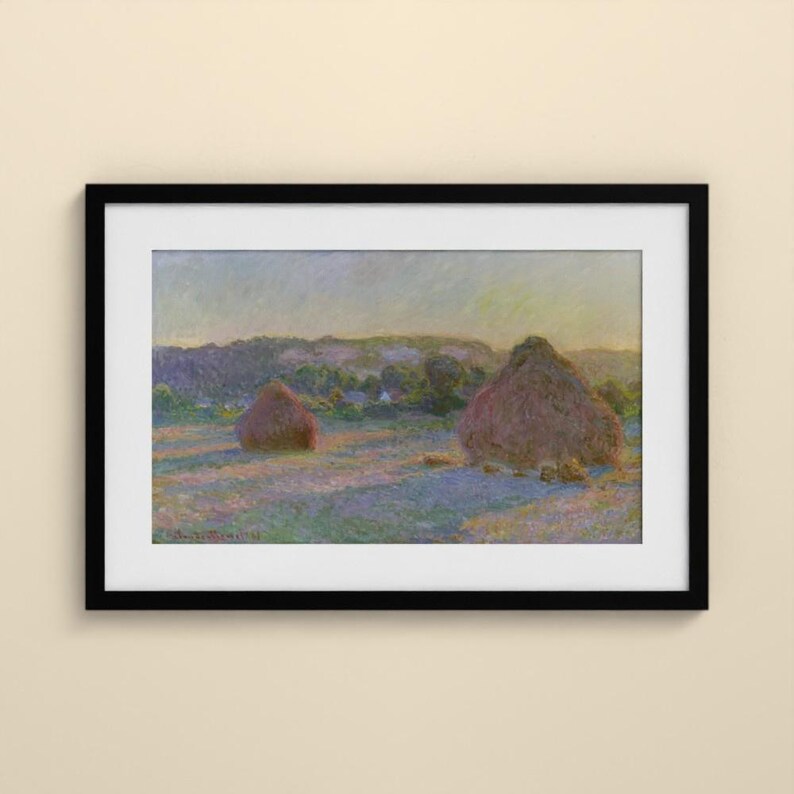 May include: A framed landscape painting featuring two large haystacks in a field under a soft, hazy sky. The artwork displays a palette of muted purples, greens, and yellows, enclosed within a simple black frame and a white mat border.