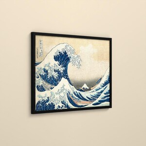 May include: A framed wall art print featuring the iconic woodblock print of a large, cresting blue wave with white foam, small boats navigating the turbulent water, and a distant mountain peak, all set against a light beige background.