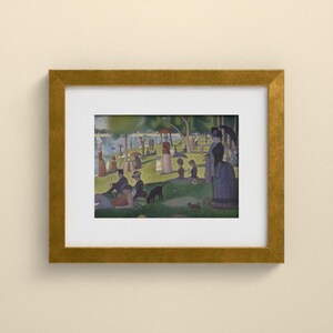 May include: A framed print of Georges Seurat's A Sunday Afternoon on the Island of La Grande Jatte, featuring a park scene with figures, trees, and a river, enclosed in a textured gold frame with a wide white mat border.
