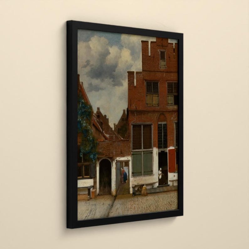 May include: A framed print of a painting depicting a Dutch street scene with red brick buildings, arched doorways, and cobblestone paths under a cloudy sky. The artwork features architectural details, green shutters, and figures in a courtyard.