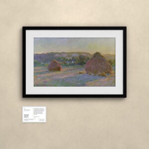 May include: A framed landscape painting depicting two haystacks in a field under a soft sky, with visible brushstrokes in shades of yellow, purple, and green. Below the frame is a small white informational card with printed text.
