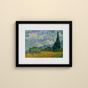 May include: A framed art print featuring a landscape painting with a golden wheat field, a tall dark green cypress tree, and a swirling blue and white sky. The artwork is enclosed in a simple black frame with a white mat border.