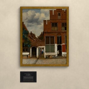 May include: A framed oil painting depicting a Dutch street scene with red brick buildings, a cobblestone courtyard, and a cloudy sky. The artwork features architectural details including multi-paned windows and a small doorway. A black informational plaque is below.