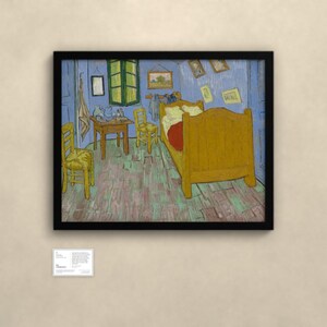 May include: A framed print of Vincent van Gogh's Bedroom in Arles painting, featuring a yellow bed, two wooden chairs, a small table, and blue walls, displayed in a black frame with a small informational plaque mounted below the artwork.