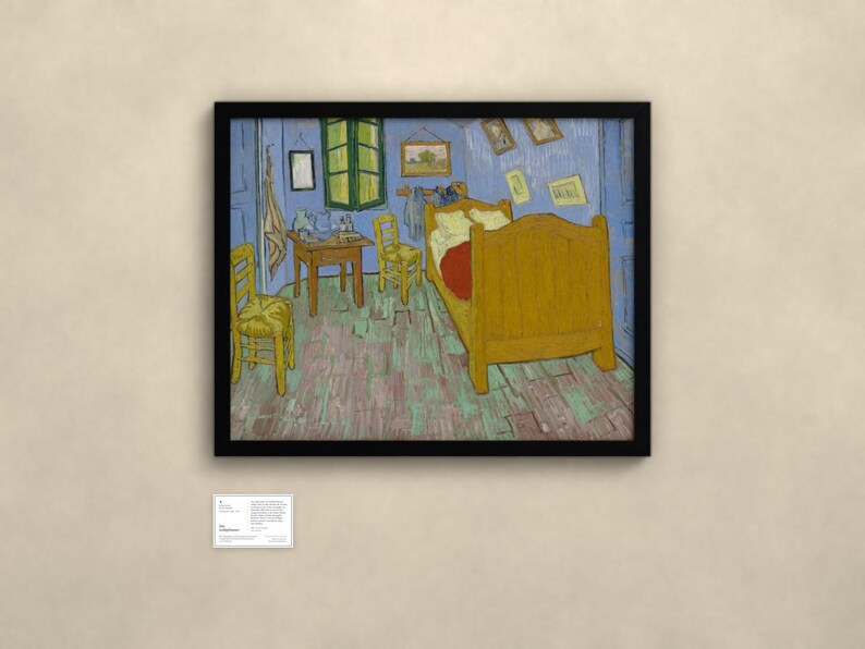 May include: A framed print of Vincent van Gogh's Bedroom in Arles painting, featuring a yellow bed, two wooden chairs, a small table, and blue walls, displayed in a black frame with a small informational plaque mounted below the artwork.