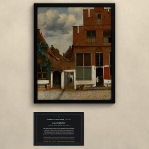 Op de afbeelding: Een ingelijste print van Johannes Vermeer's schilderij Het Straatje, met een rood bakstenen Nederlands huis met trapgevel, groene luiken en een geplaveid steegje. Onder de lijst bevindt zich een zwart plaatje met witte tekst over het kunstwerk.
