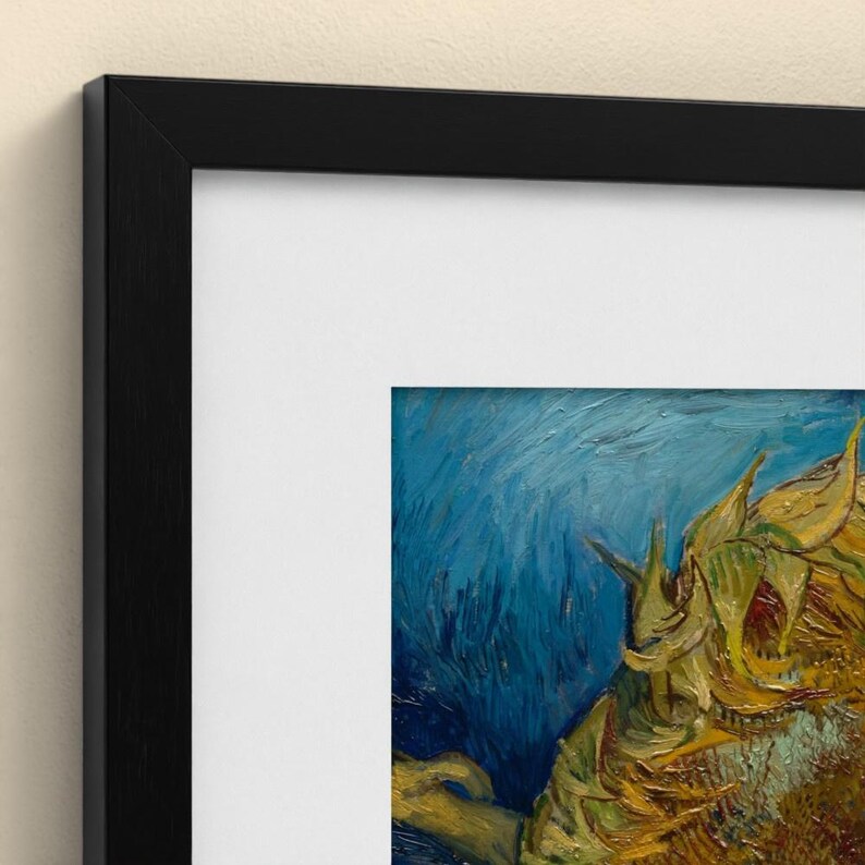 May include: A framed art print featuring a close-up of a sunflower painting with thick, textured brushstrokes in shades of yellow and gold against a deep blue background, enclosed in a simple black frame with a wide white mat border.