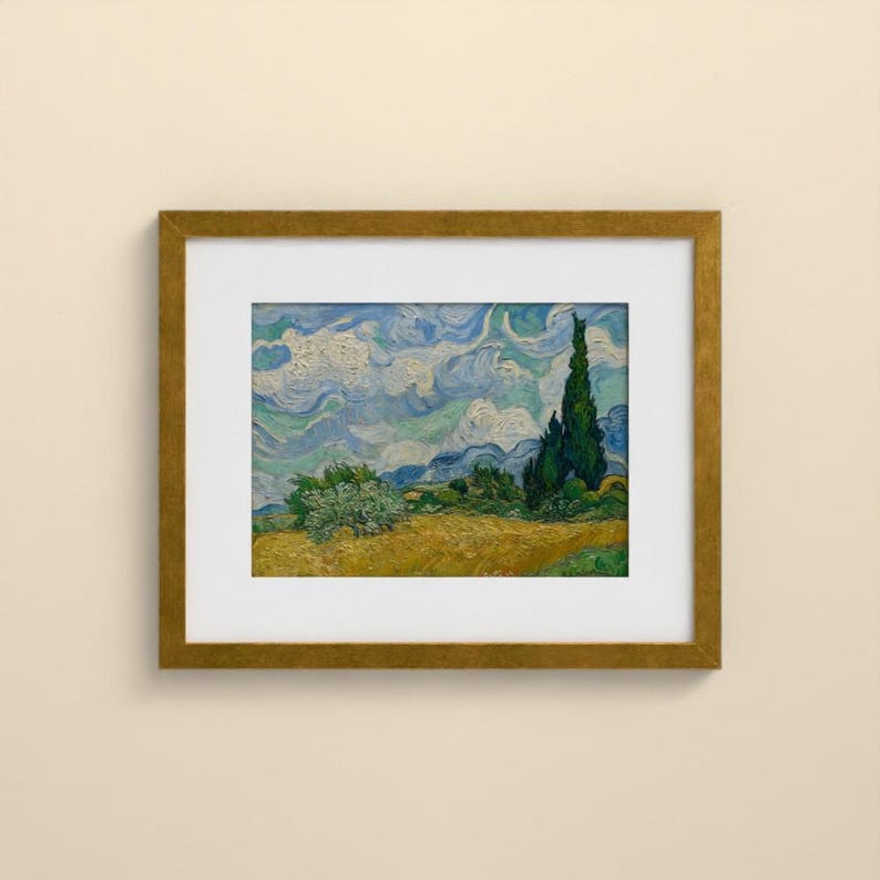May include: A framed art print featuring a landscape painting with a golden yellow wheat field, a dark green cypress tree, and a swirling blue and white sky. The artwork is enclosed in a simple gold-toned frame with a white mat border.
