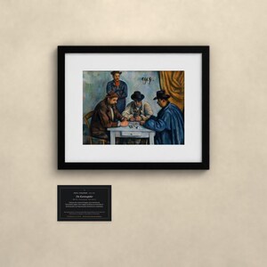 May include: A framed art print of Paul C&eacute;zanne's The Card Players, featuring four figures seated around a table playing cards. The painting is enclosed in a black frame with a white mat. Below the frame is a small black informational plaque.