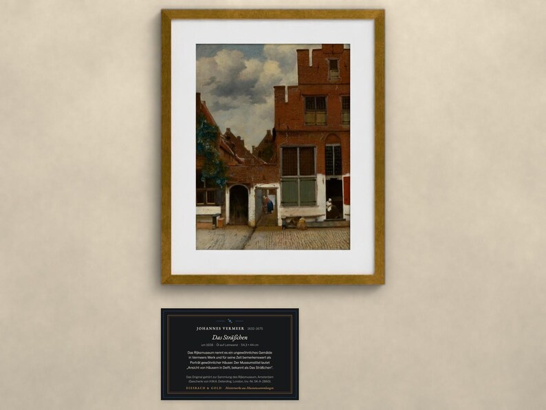 May include: A framed print of Johannes Vermeer's painting The Little Street, depicting a red brick Dutch house facade with a cobblestone alleyway under a cloudy sky, accompanied by a black informational plaque with white text.