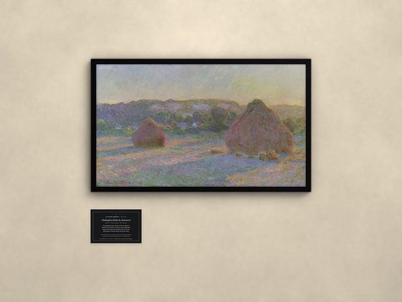 May include: A framed landscape painting featuring two large haystacks in a field under a soft sky, with a small black informational plaque below. The artwork displays muted tones of purple, gold, and green, capturing a rural scene.