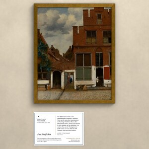Op de afbeelding: Een ingelijst olieverfschilderij met een Nederlandse straatsc&egrave;ne met rode bakstenen gebouwen, een bewolkte lucht en figuren op een binnenplaats. Onder het schilderij bevindt zich een witte informatiekaart met zwarte tekst getiteld Das Str&auml;&szlig;chen van Johannes Vermeer.