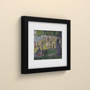May include: A framed print featuring a reproduction of Georges Seurat's A Sunday Afternoon on the Island of La Grande Jatte. The artwork is encased in a black frame with a white mat, displaying figures in a park setting by the water.