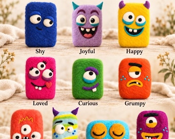 May include: A collection of ten rectangular handmade felted soaps labeled Rooted @ Hedgecreek Farm Meet the Monsters. Each soap features a unique monster face with distinct colors and expressions including shy, joyful, happy, loved, curious, grumpy, surprised, confused, sleepy, and silly.