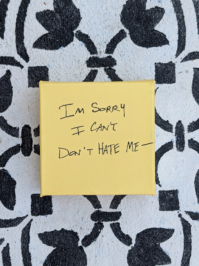 May include: A yellow canvas with black handwritten text that reads "I'm sorry I can't Don't hate me - "