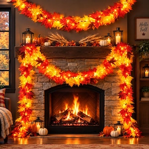 May include: A decorative garland featuring artificial maple leaves in shades of red, orange, and yellow, illuminated by integrated warm white string lights. The garland is draped around a stone fireplace mantel with lanterns and pumpkins.