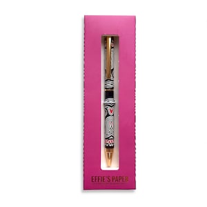 May include: A black and white patterned pen with red accents in a pink box. The box has the text "EFFIE'S PAPER STATIONARY & WHATNOT!" on the bottom.