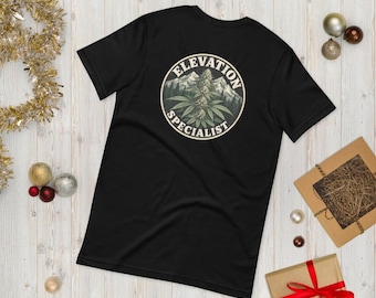 May include: A black short-sleeve t-shirt featuring a circular graphic on the back. The design depicts a cannabis plant centered in front of mountain peaks, surrounded by the text Elevation Specialist in a circular white border.