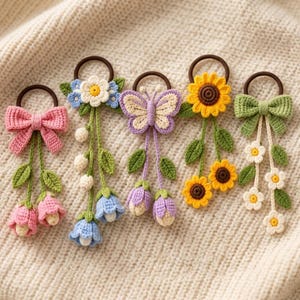 Può includere: Cinque elastici per capelli all'uncinetto con motivi floreali e a farfalla. I design includono un fiocco rosa con tulipani, un fiore bianco con campanule blu, una farfalla viola, un girasole giallo e un fiocco verde con fiori bianchi.