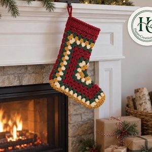 May include: A crocheted Christmas stocking featuring a granny square pattern in deep red, forest green, and cream yarn. The stocking has a thick red cuff at the top and a hanging loop. A circular logo with the text HappyCreationsWithUs is visible.