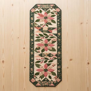 Modern Patchwork Bloom quilted table runner PDF pattern with dusty pink floral blocks, sage green leaves, cream fabric, geometric patchwork accents, and dark green floral borders. Three large flower motifs and leafy branches create an elegant botanical design for dining tables. Finished size 16 x 54 inches (40.6 x 137.2 cm).