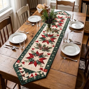 Puede incluir: Un camino de mesa acolchado con un patrón repetitivo de estrellas rojas, ramas de pino verdes y piñas sobre un fondo crema con un borde verde oscuro. El camino está centrado en una mesa de comedor de madera con platos blancos.
