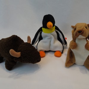 May include: Three plush toys: a brown buffalo, a black and white penguin with a yellow scarf, and a brown squirrel.