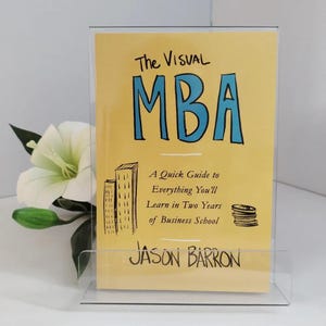 May include: A yellow book titled The Visual MBA: A Quick Guide to Everything You'll Learn in Two Years of Business School by Jason Barron, featuring a hand-drawn illustration of two skyscrapers and a stack of coins on the cover.