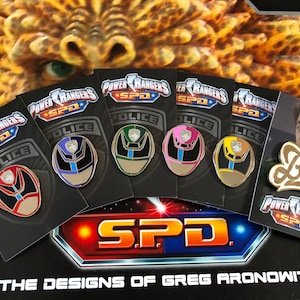 May include: Five Power Rangers SPD enamel pins featuring the red, blue, green, pink, and yellow ranger helmets. A gold 'Bully' pin with the Power Rangers SPD logo is also shown.