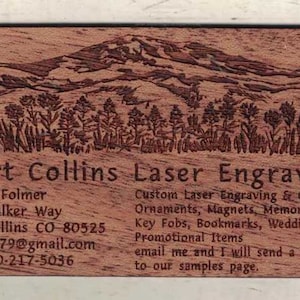 May include: A wooden business card with a laser engraved image of a mountain range and trees. The text on the card reads "Fort Collins Laser Engraving", "Robert Folmer", "400 Walker Way", "Fort Collins CO-80525", "rfolmer79@gmail.com", "cell 970-217-5036", "Custom Laser Engraving & Cutting", "Ornaments, Magnets, Memorial favors", "Key Fobs, Bookmarks, Wedding favors", "Promotional Items", "email me and I will send a link to our samples page."