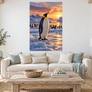 K&ouml;nnte beinhalten: Ein rechteckiger Wandkunstdruck, der einen einsamen Kaiserpinguin zeigt, der w&auml;hrend eines lebhaften Sonnenuntergangs auf eisigem Gel&auml;nde steht. Der Pinguin hat schwarze und wei&szlig;e Federn mit gelben Akzenten am Hals. Im Hintergrund steht eine Gruppe kleinerer Pinguine auf dem Eis vor schneebedeckten Bergen und einem leuchtend orangefarbenen Himmel.