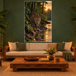 K&ouml;nnte beinhalten: Ein rechteckiger Wandkunstdruck, der einen Jaguar zeigt, der am Ufer eines Flusses in einer dichten Dschungelumgebung kauert. Die Szene wird von einem warmen, goldenen Sonnenuntergang beleuchtet, der sich im Wasser spiegelt und das gefleckte Fell des Jaguars hervorhebt.