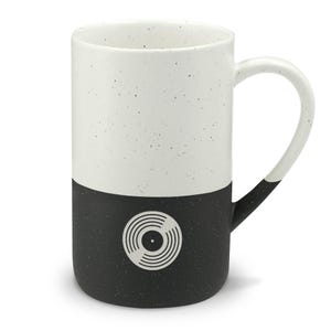 May include: A tall ceramic mug with a speckled finish, featuring a two-tone design with a white upper half and a black lower half. A white graphic of a vinyl record is centered on the black section. The handle is white at the top and black at the base.