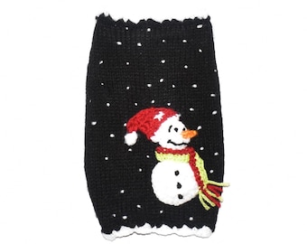 May include: Black knitted dog sweater with a white snowman design. The snowman has a red hat, a green scarf, and a carrot nose.